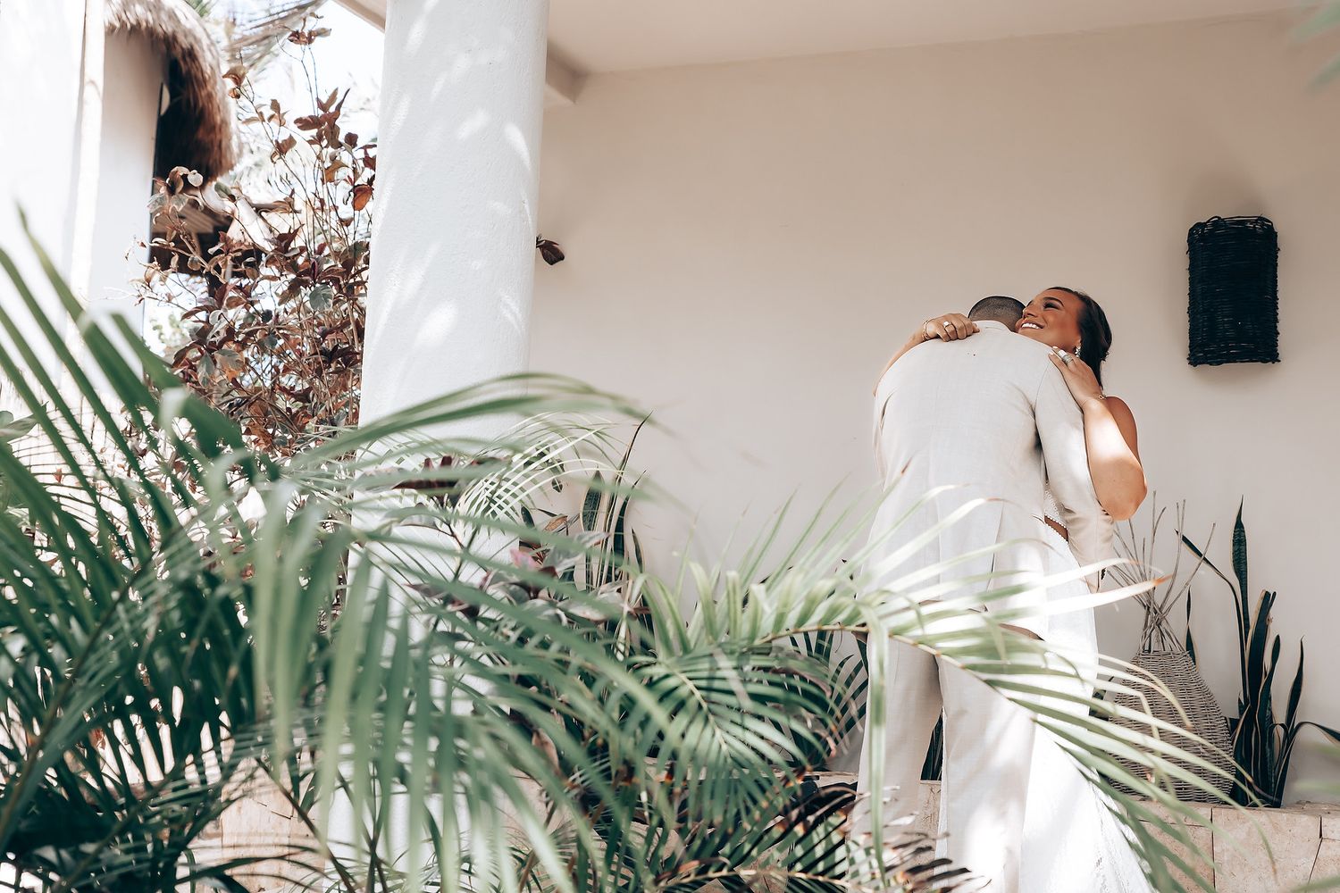 A romantic beach wedding ceremony setup with tropical palm trees and white decor against turquoise waters.