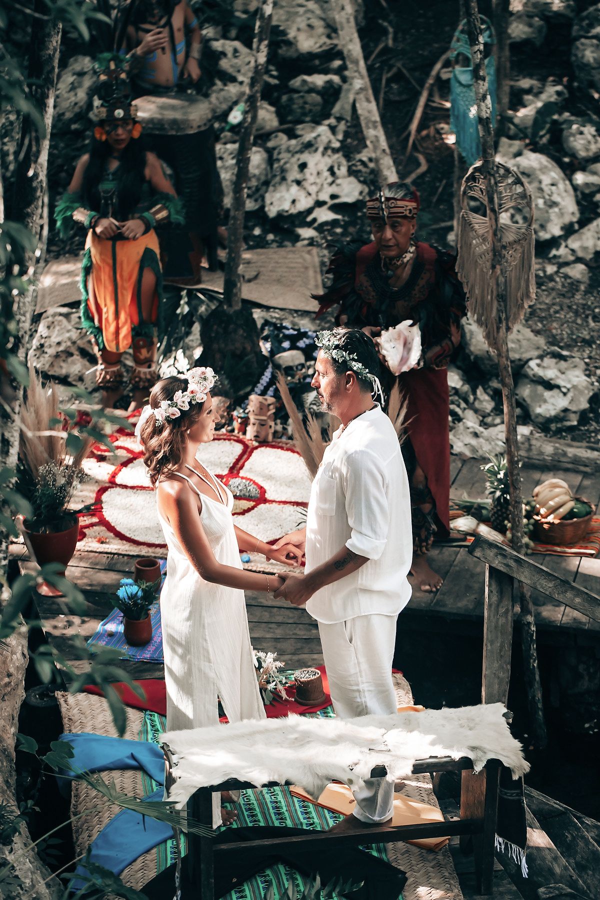 A wedding ceremony taking place in a lush, tropical setting with various decorations and people in attendance.
