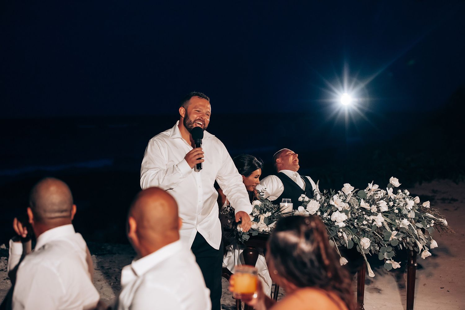 Evening wedding reception under string lights with guests dancing and celebrating.