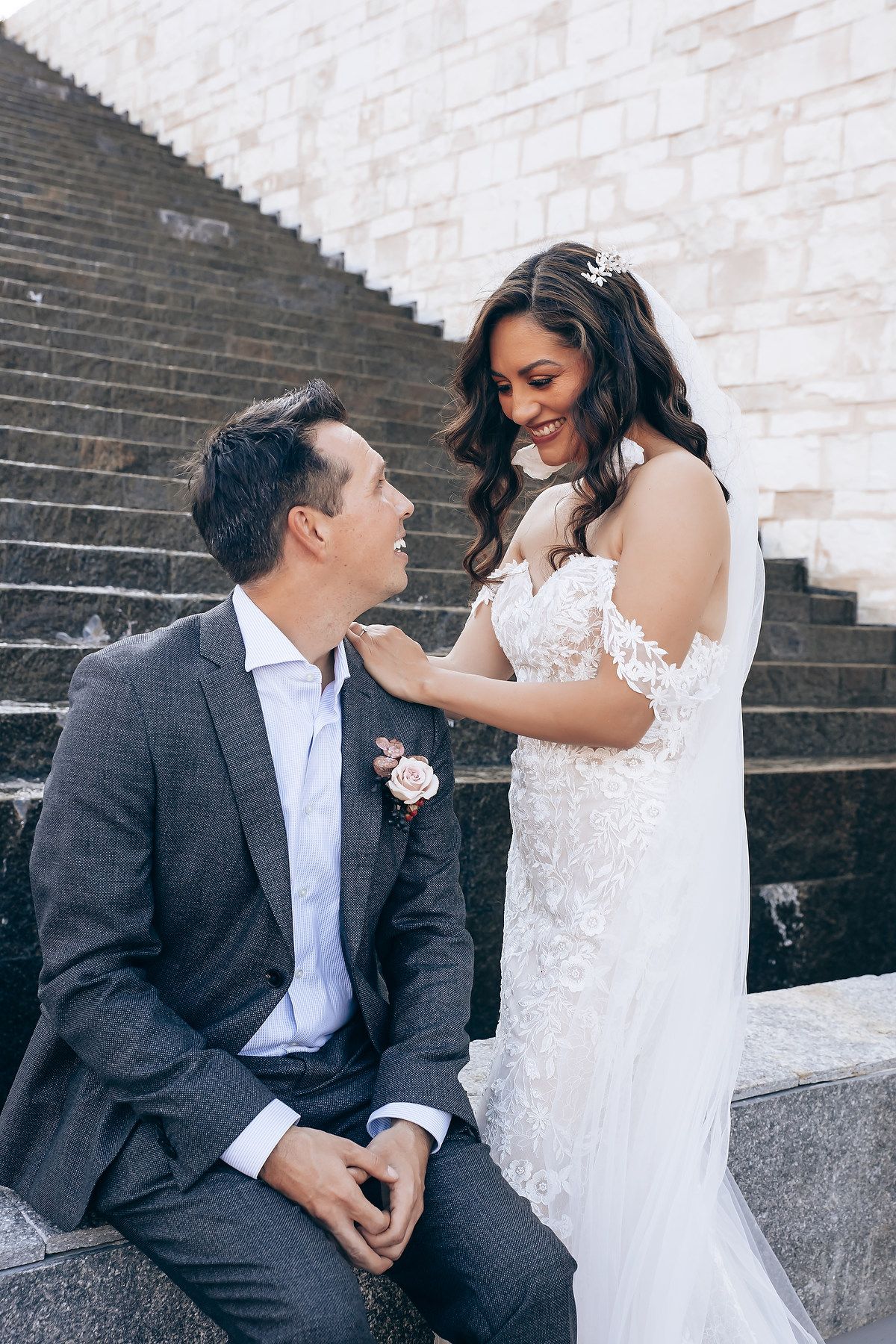 A romantic wedding moment captured on stone steps with the couple in elegant attire sharing a tender interaction.