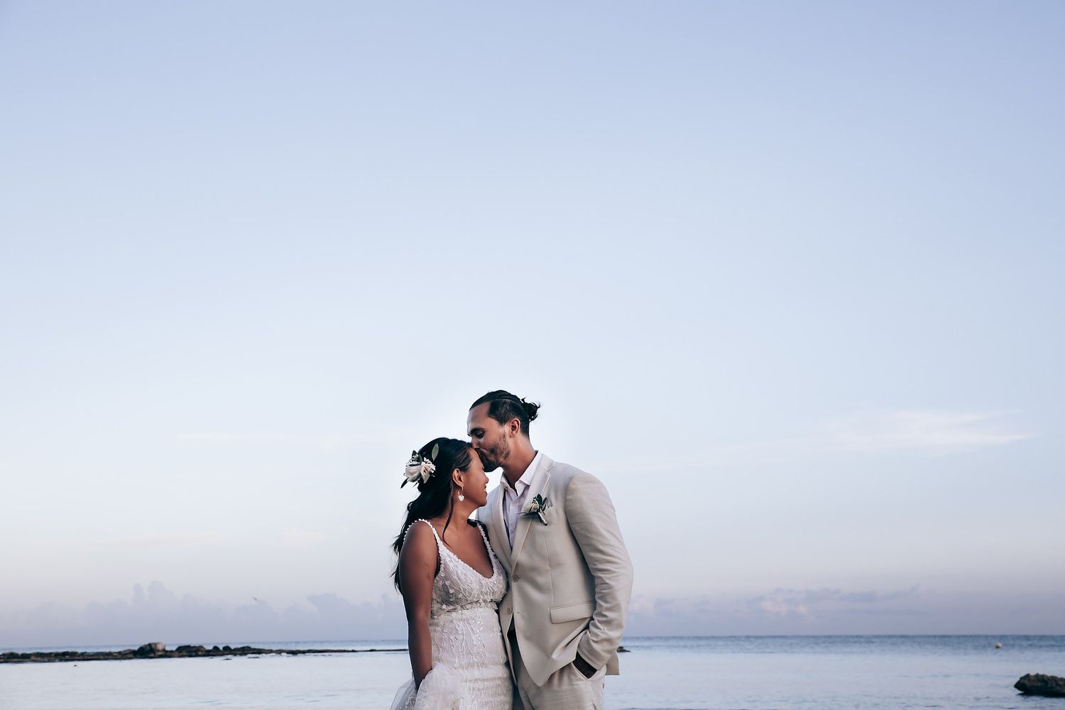Romantic beach wedding ceremony against a soft blue sky backdrop.