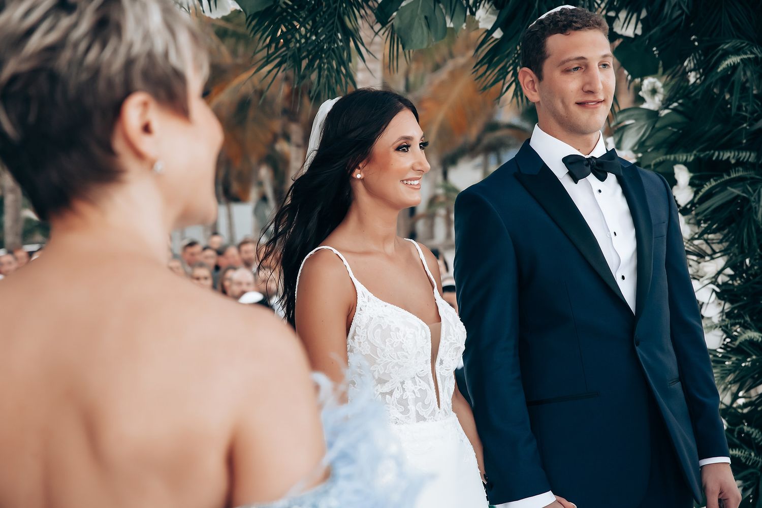 Wedding ceremony under tropical palm trees with formal attire.