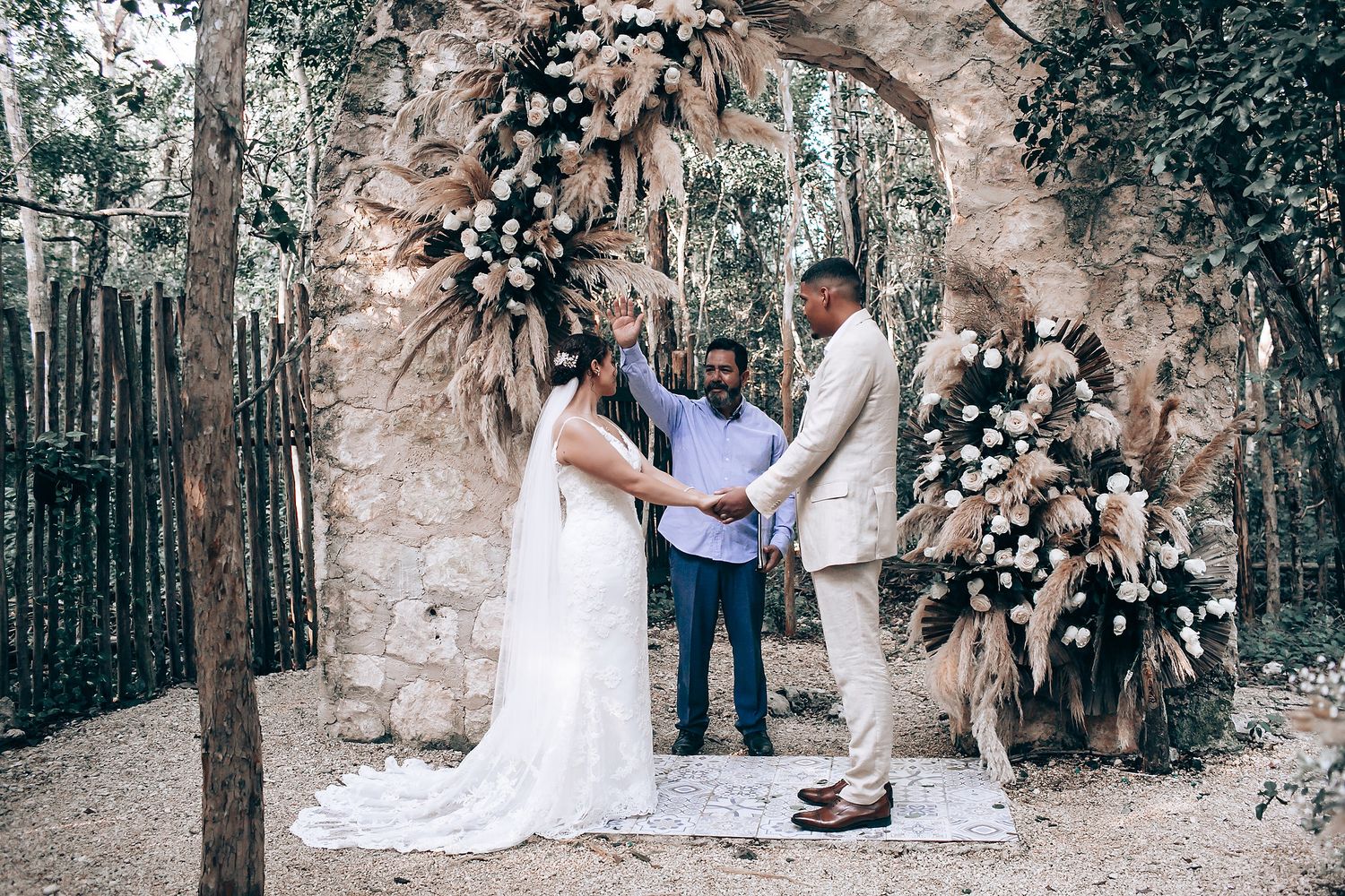 Elegant outdoor wedding ceremony with white floral decorations in a forest.