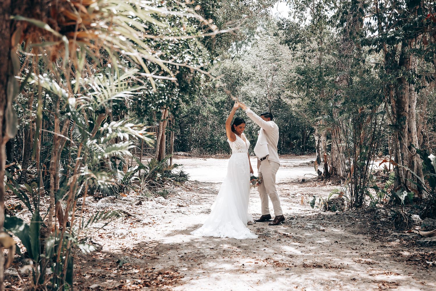 Wedding couple shares intimate moment on sunlit forest path.