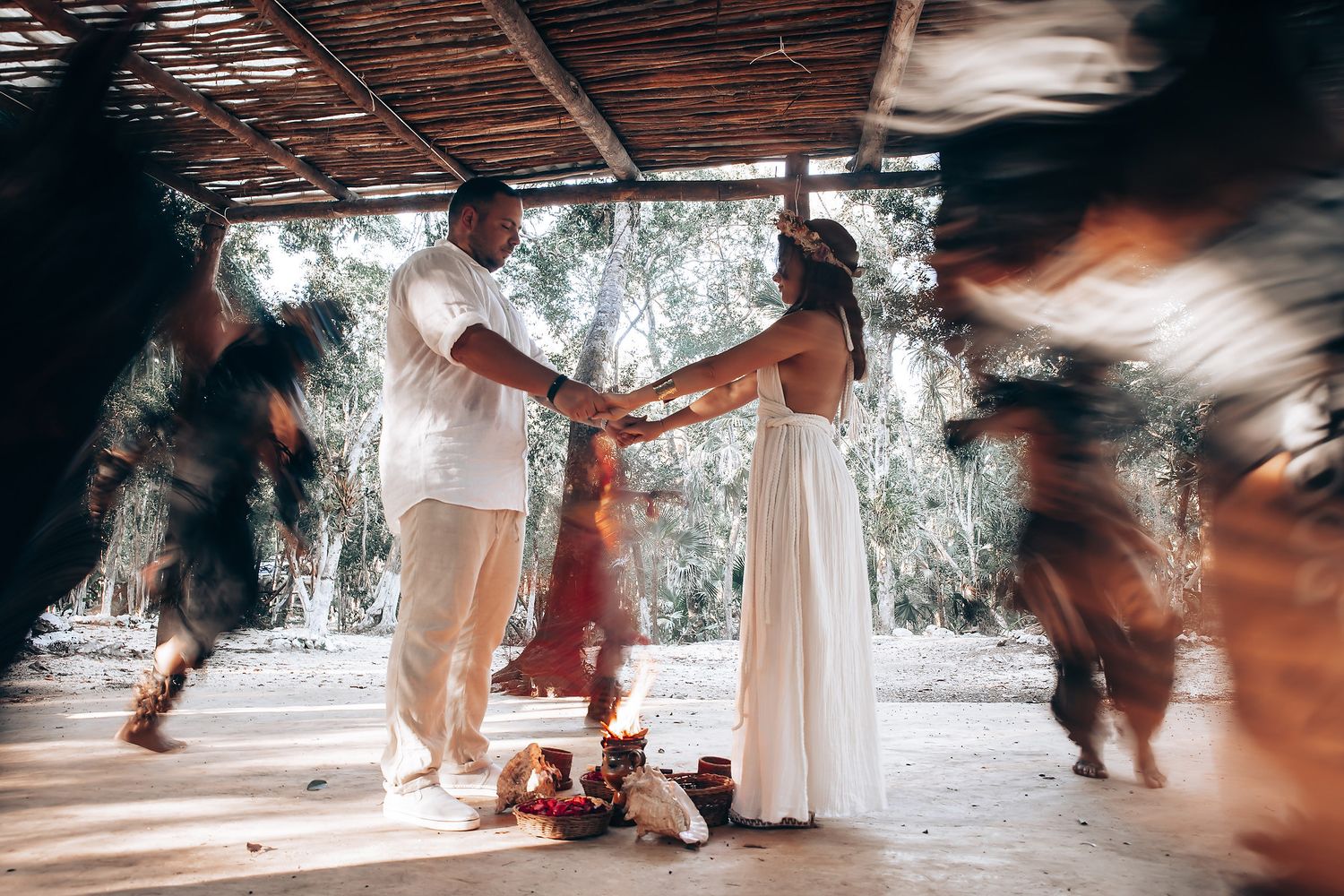 Motion-blurred dancers move beneath a wooden canopy structure during a celebration.
