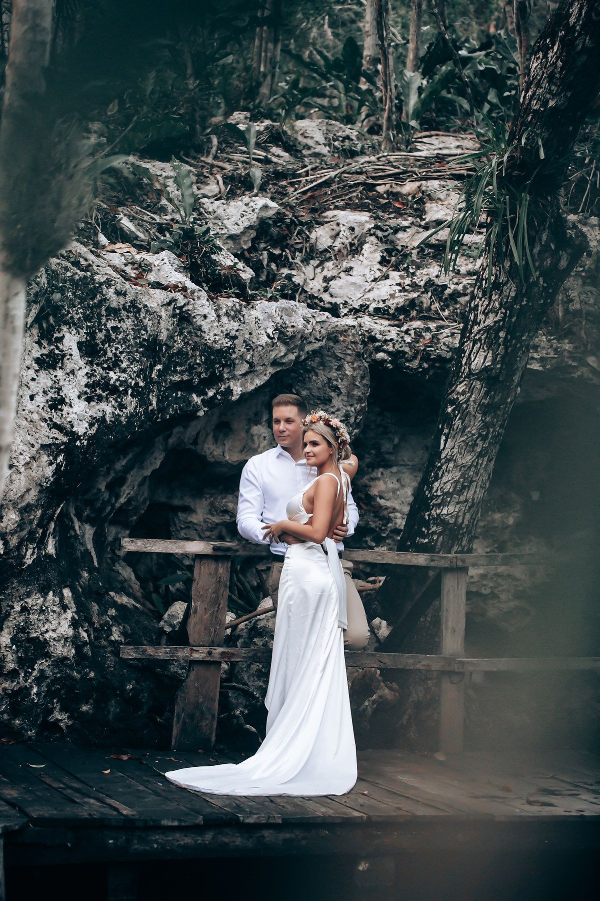 Romantic portrait on wooden platform against dramatic cave backdrop.