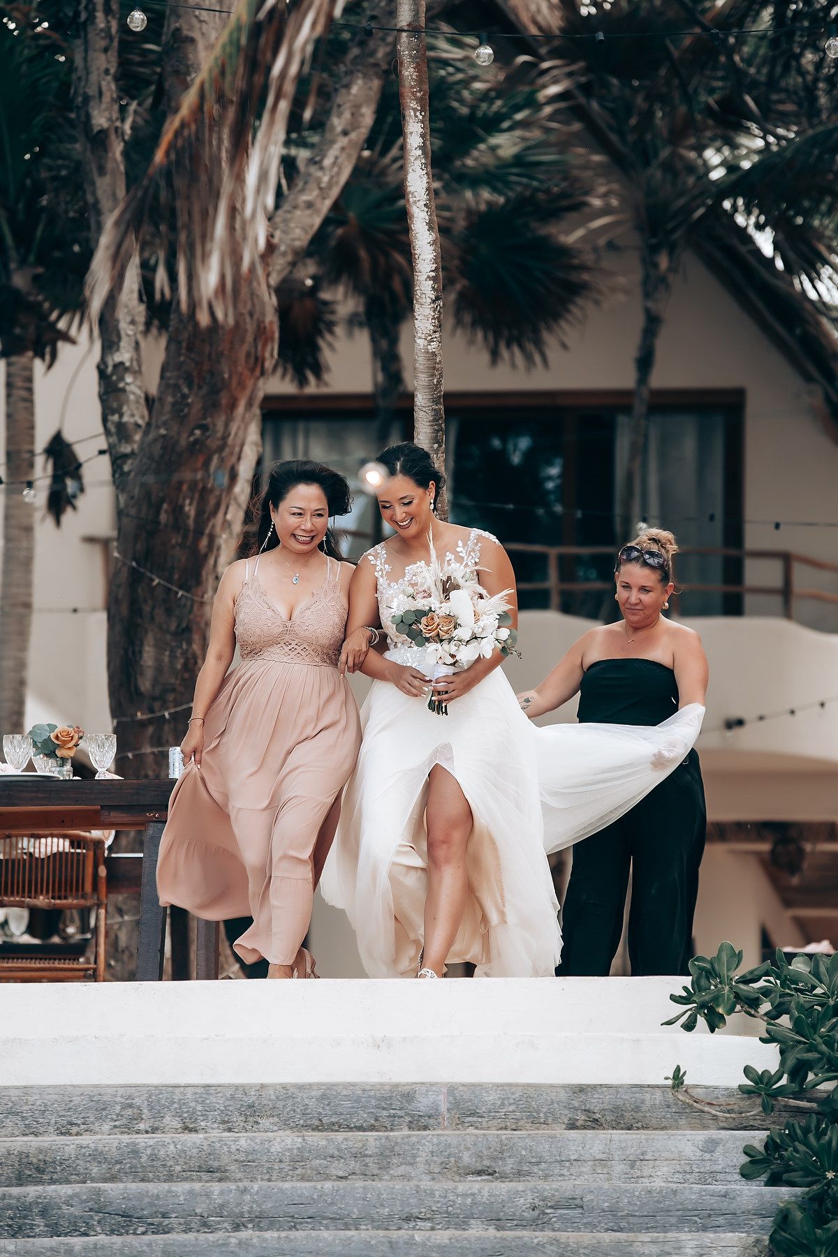 Wedding party in blush and white dresses posing on outdoor steps.