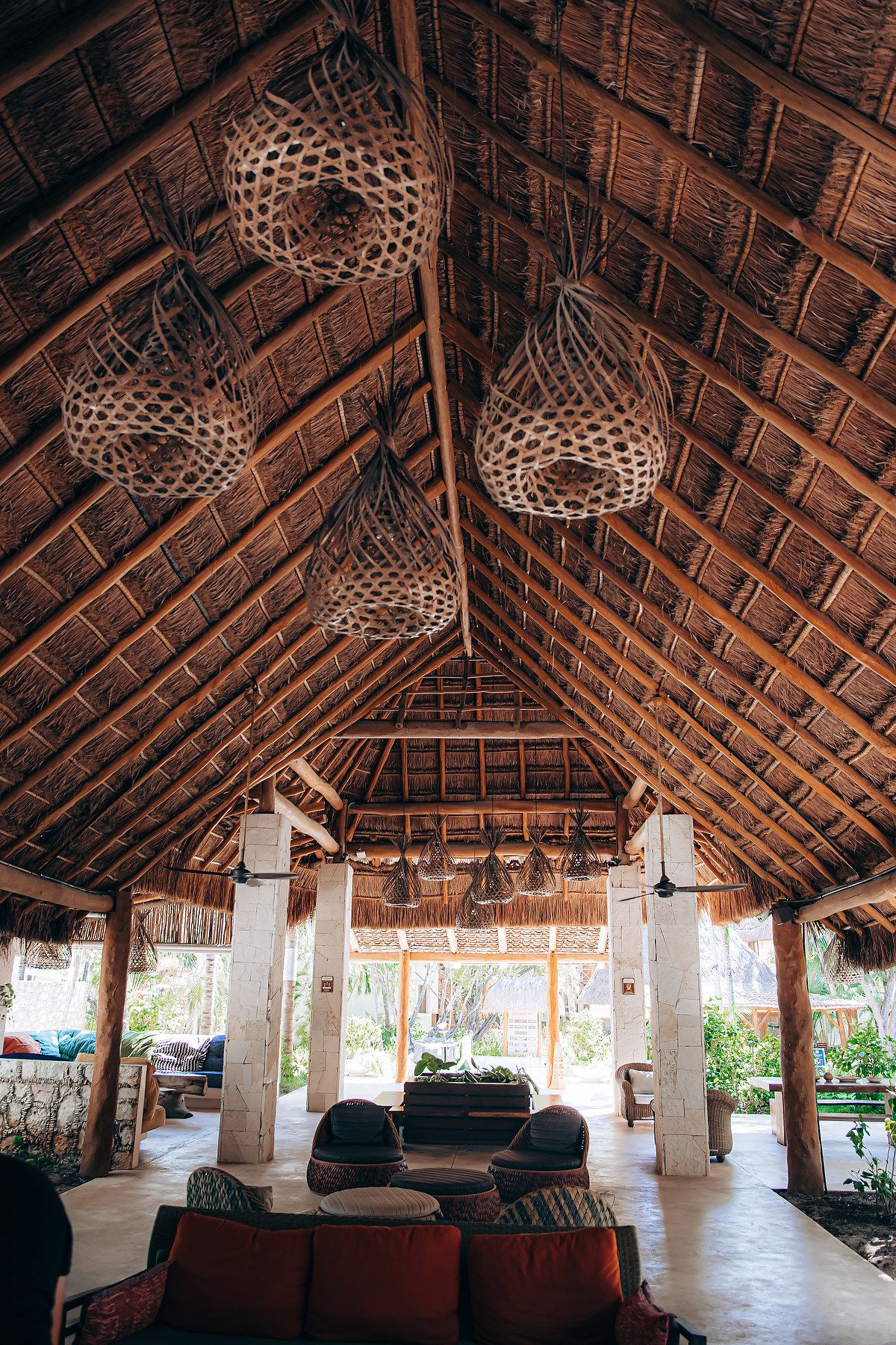 Interior view of a tropical resort lounge with thatched palm roof and comfortable seating areas.