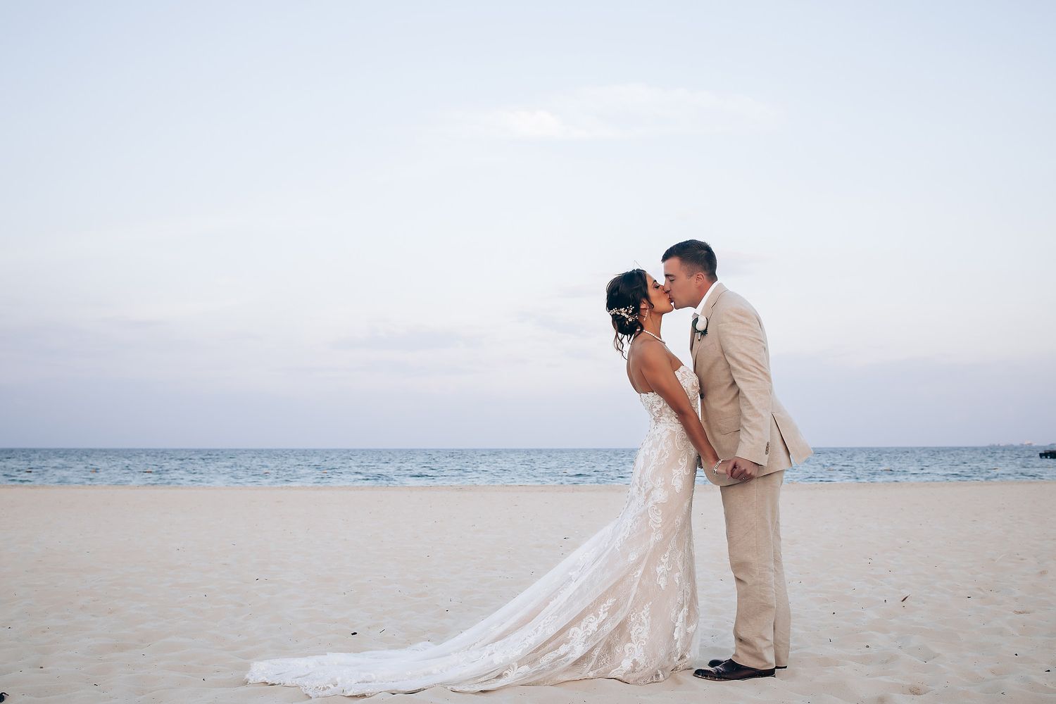 Elegant beachside wedding portraits with couple walking along pristine white sand shoreline.