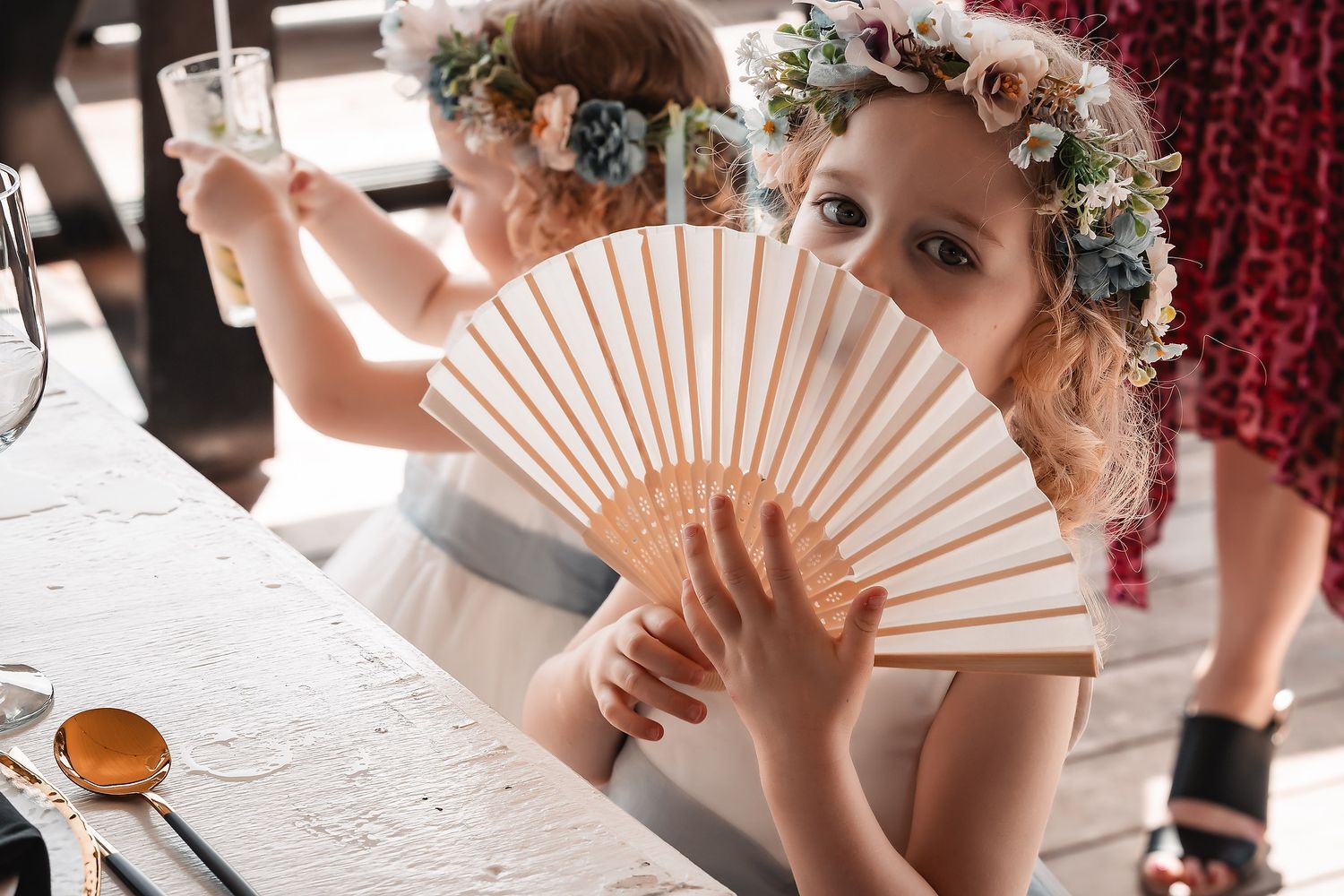 Wedding party members hold decorative white fans during an elegant indoor celebration.