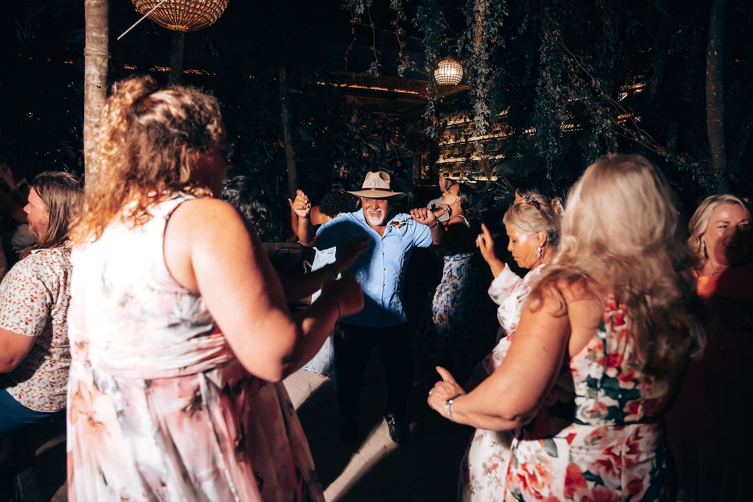 People dancing and socializing at a dimly lit indoor party with festive decorations.