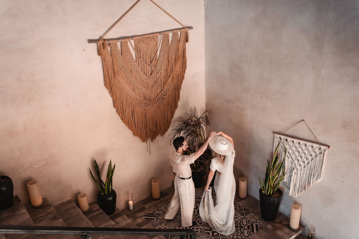 Artistic wedding portraits against neutral wall with bohemian macrame decor.