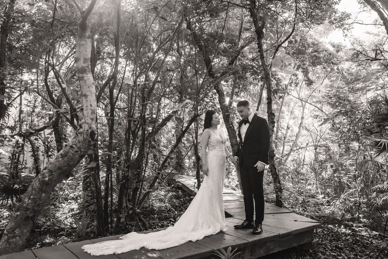 Newlyweds exchange vows on an elevated wooden deck surrounded by a forest canopy.