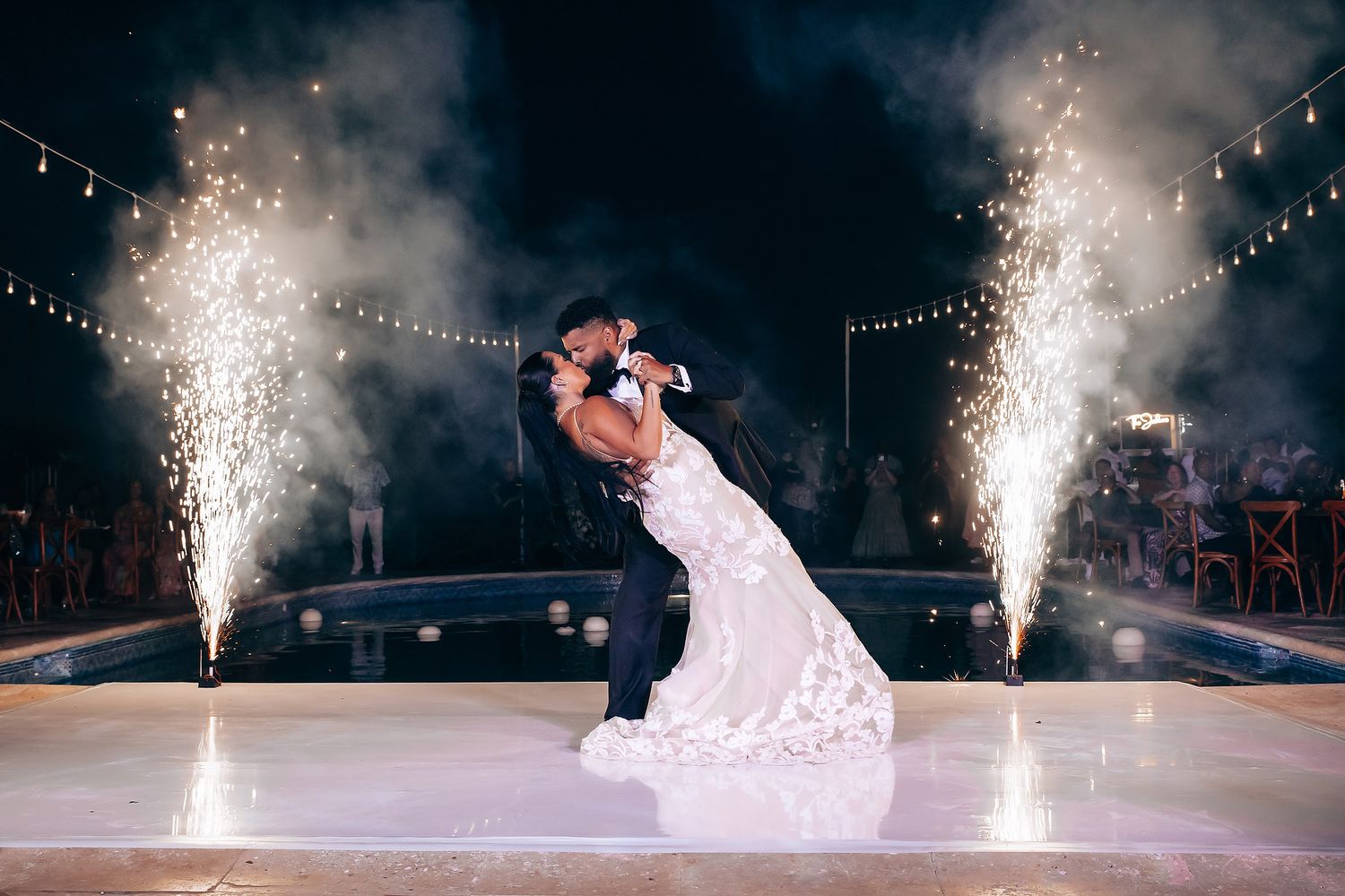 Dramatic sparkler fountains illuminate a dance floor during a wedding first dance.
