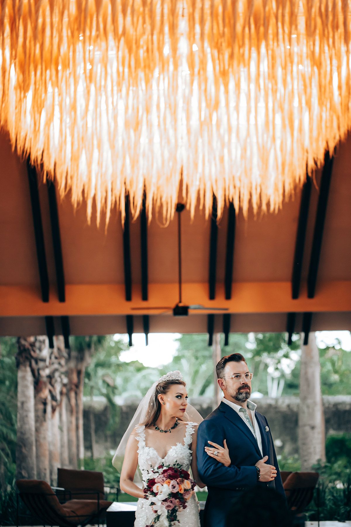 A couple dances beneath a stunning ceiling installation of cascading warm lights at an elegant indoor venue.