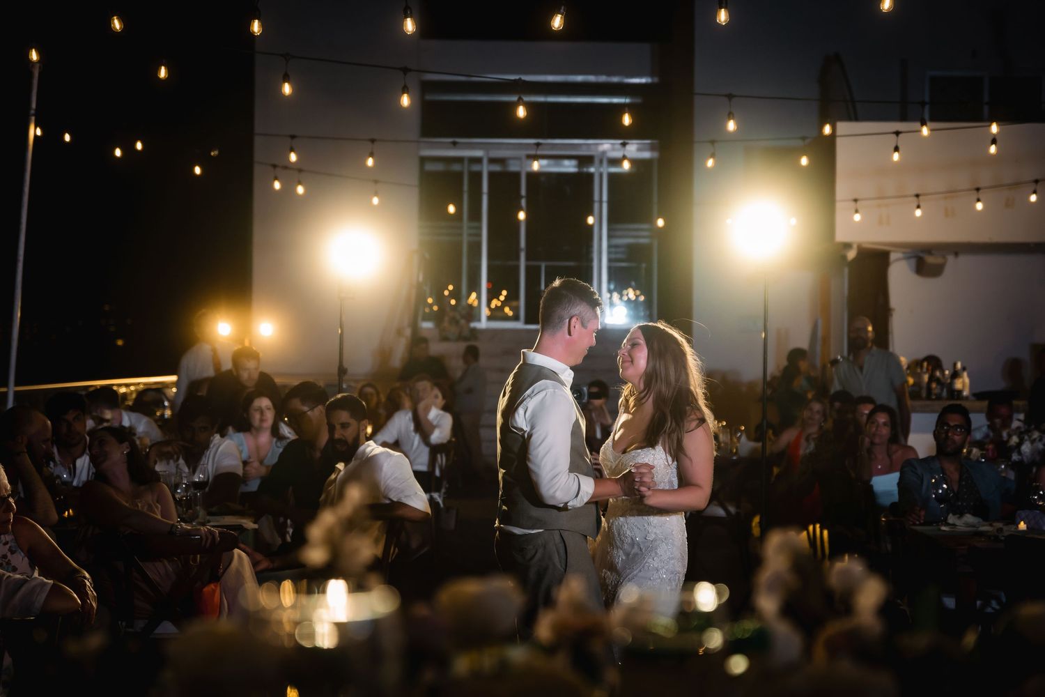 Wedding celebration at night with warm ambient lighting and guests mingling.
