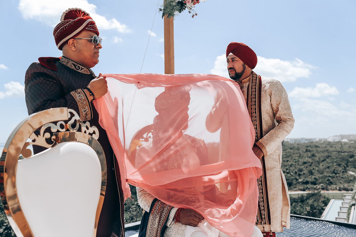 Outdoor wedding celebration with pink decor elements against a blue sky backdrop.