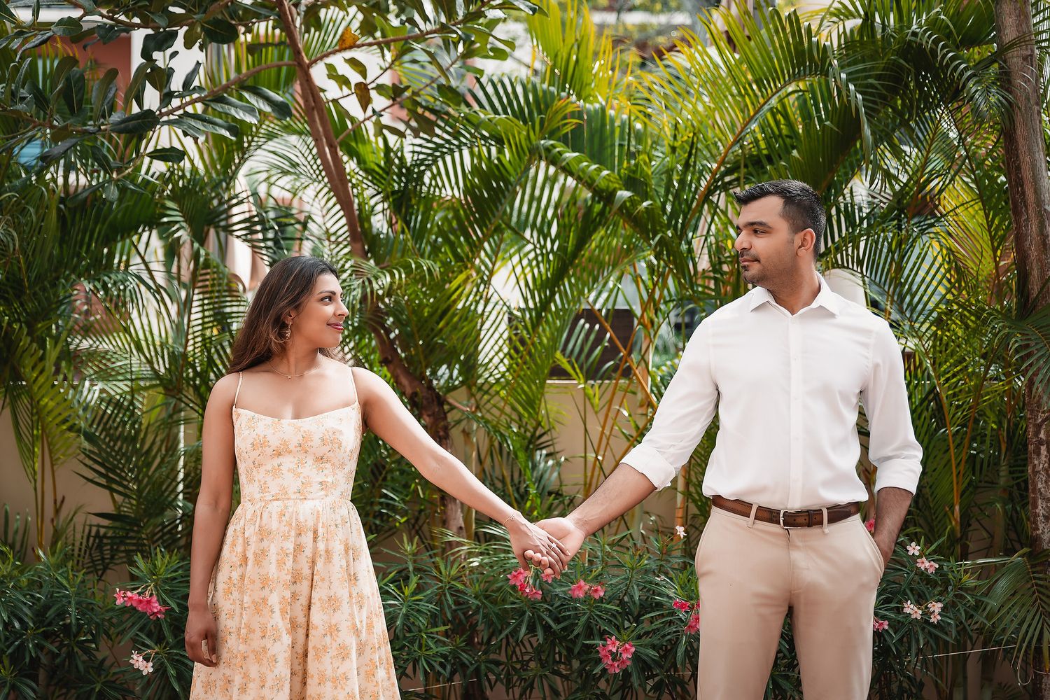 Couple poses together in a lush tropical garden with palm trees and vibrant greenery.