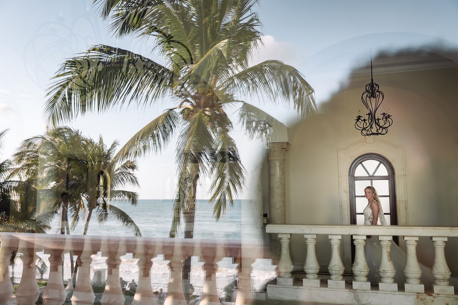 Palm trees frame an elegant Mediterranean-style venue with white balustrades.
