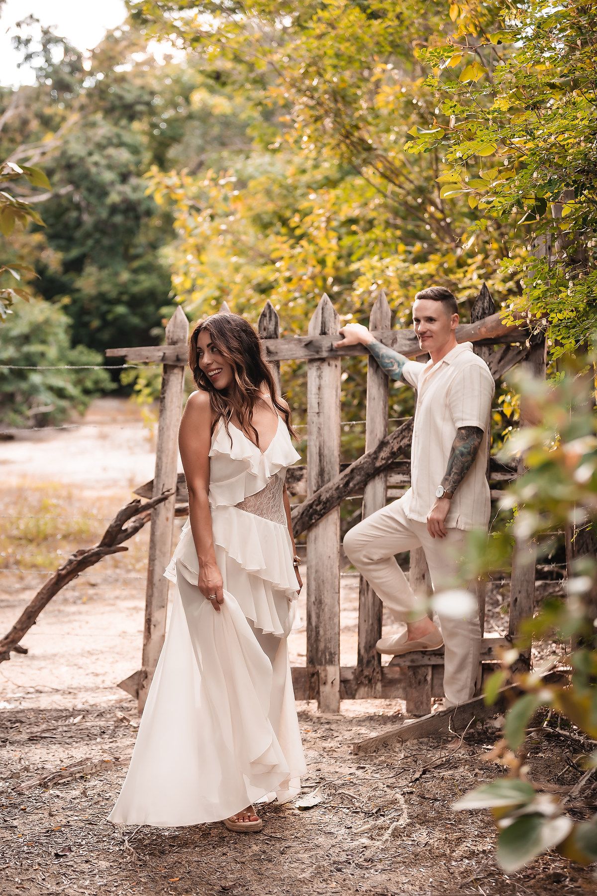A dreamy autumn scene with a flowing white dress and casual attire against golden foliage.
