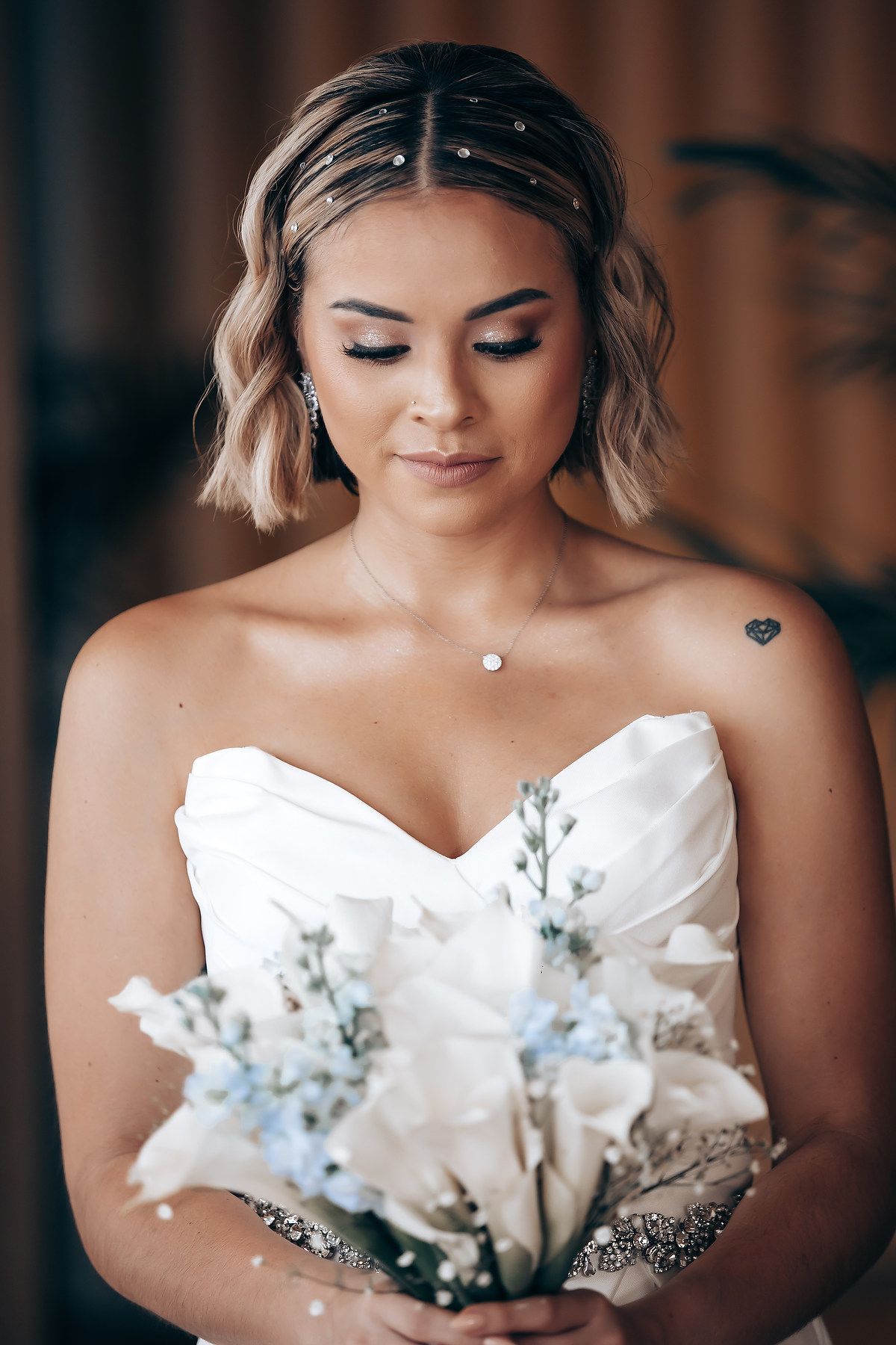 Bride in white strapless dress holding delicate blue and white floral bouquet.