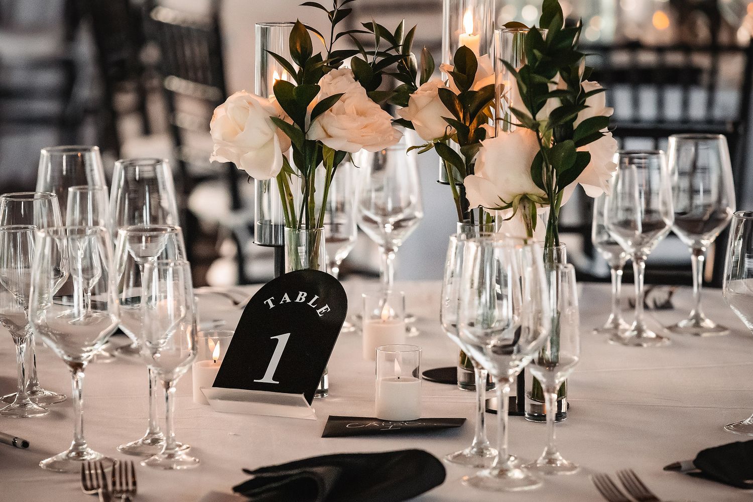 Elegant wedding reception table setting with wine glasses and place settings in neutral tones.