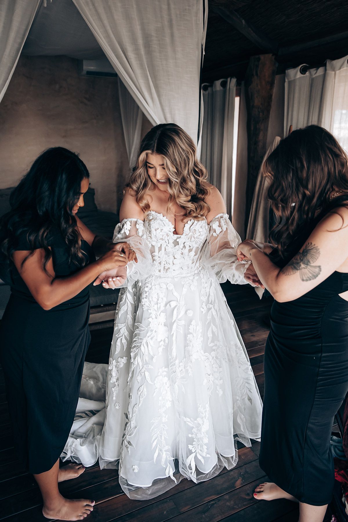 Behind-the-scenes sequence of people helping with a white lace wedding dress preparation.