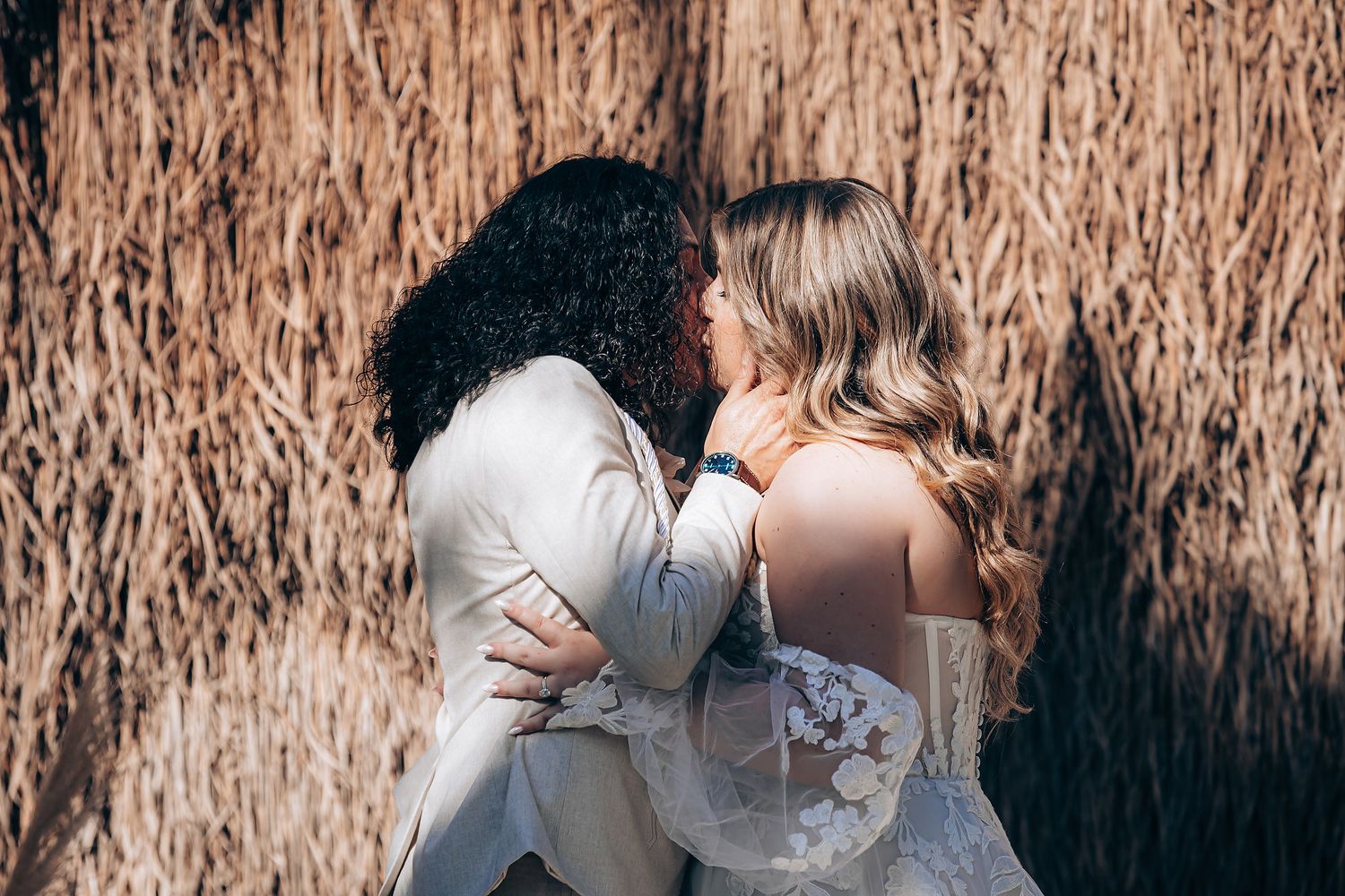 Couple embracing in front of tall brown reeds during an intimate outdoor photo session.
