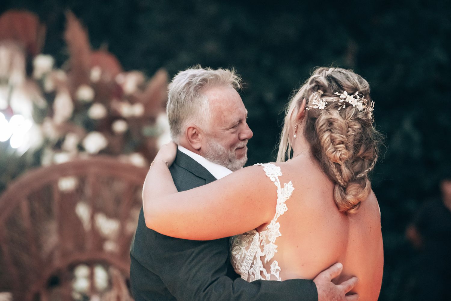 Emotional father daughter first dance embrace at wedding reception with floral backdrop.