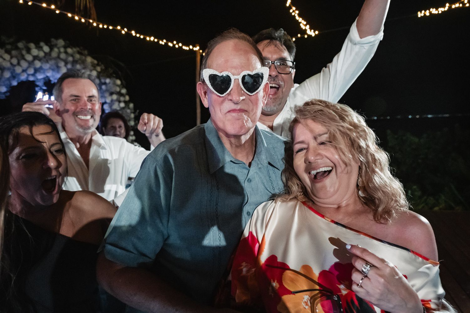 Wedding guests celebrating with heart-shaped sunglasses at reception party.