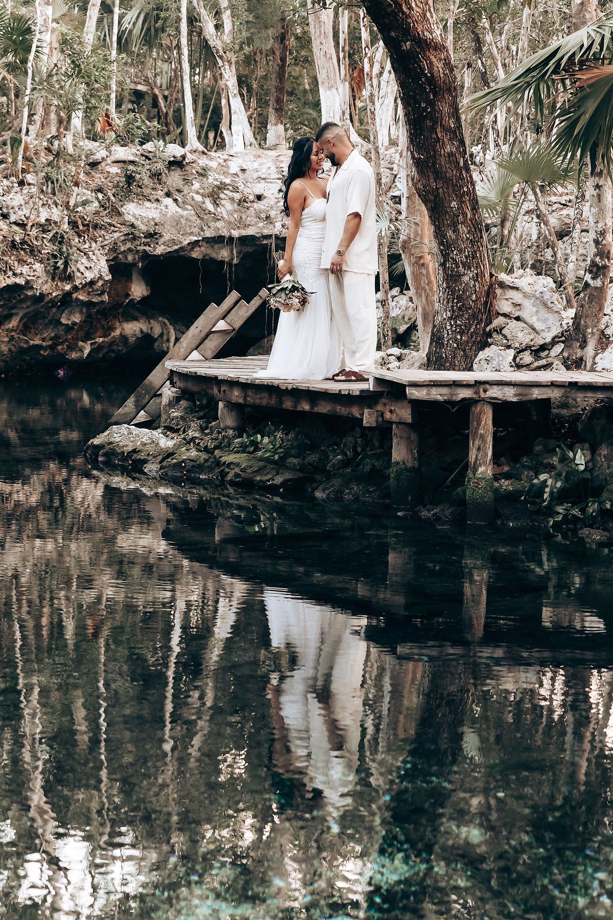 Serene waterside photo session at a natural cenote with crystal clear reflections and limestone walls.