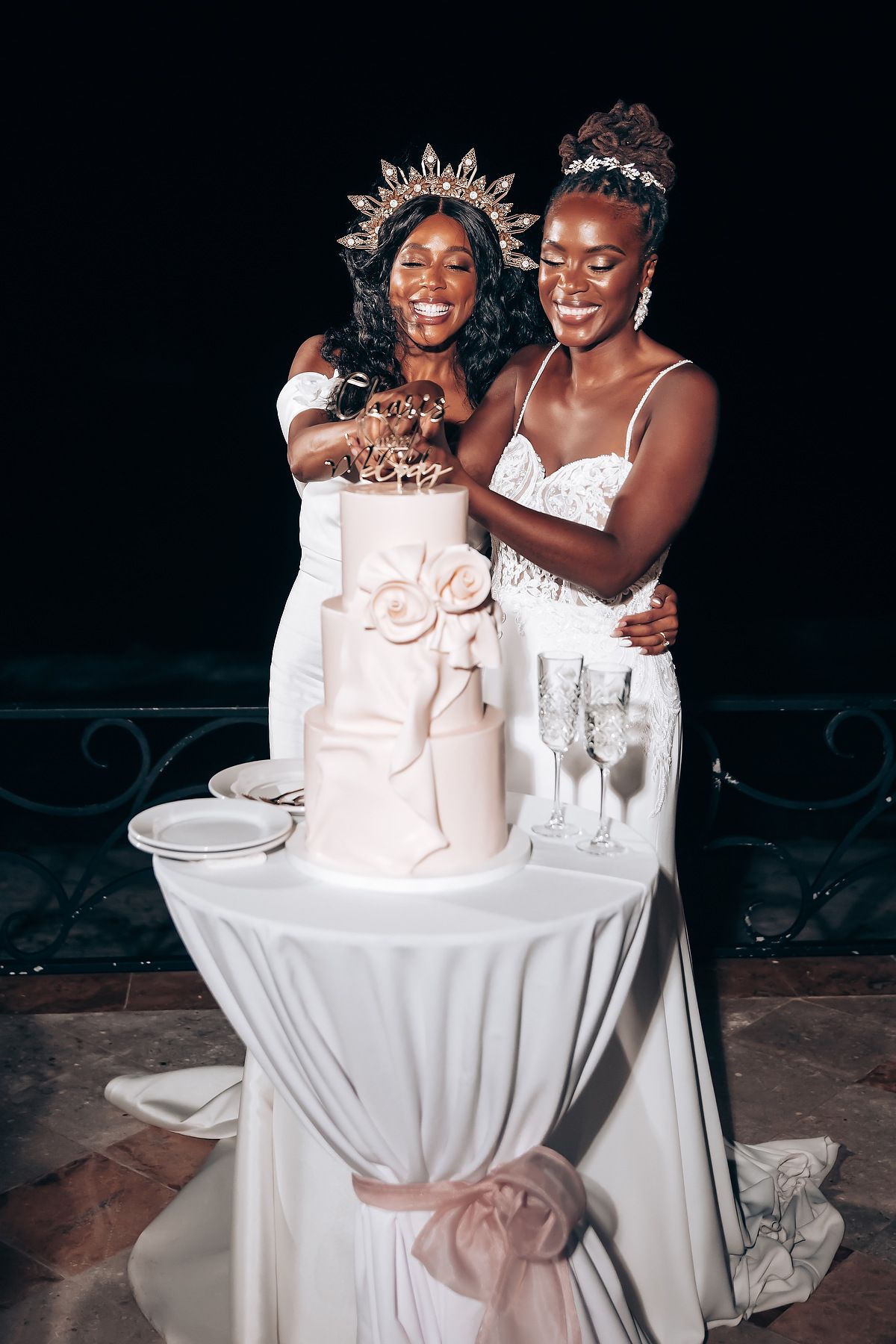 Wedding cake cutting celebration at an evening reception with white tablecloth setting.