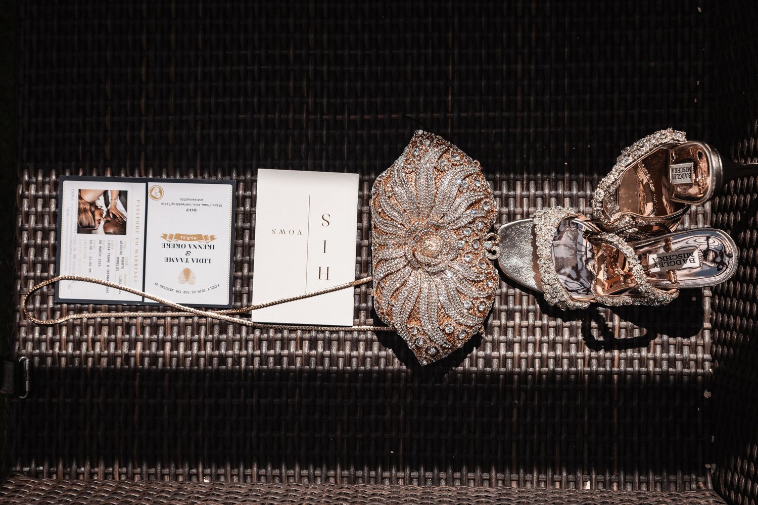 Elegant wedding flat lay featuring ornate crystal clutch, invitation suite, and decorative accessories on woven surface.