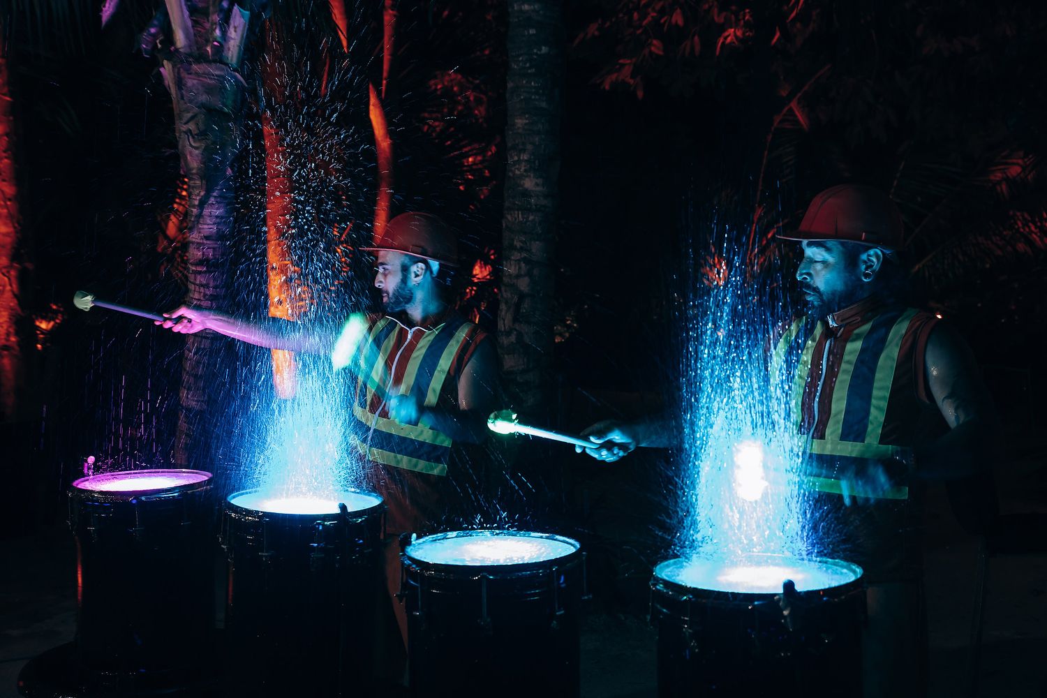 Blue spotlights create dramatic lighting effects at outdoor event.
