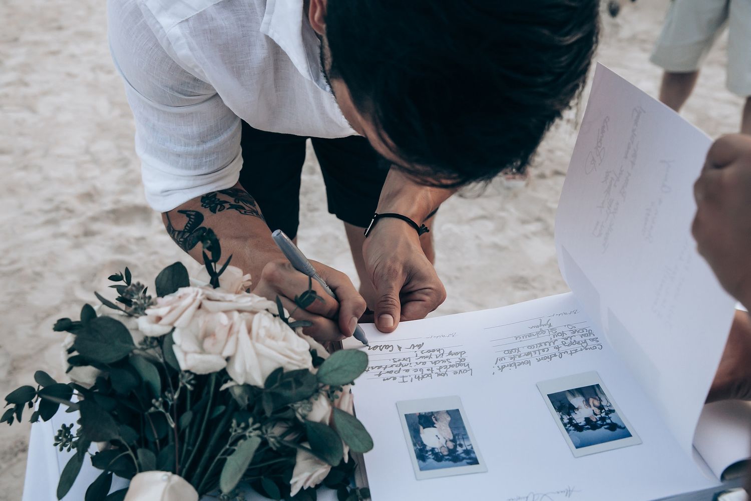 Wedding guest book being signed with floral decorations.