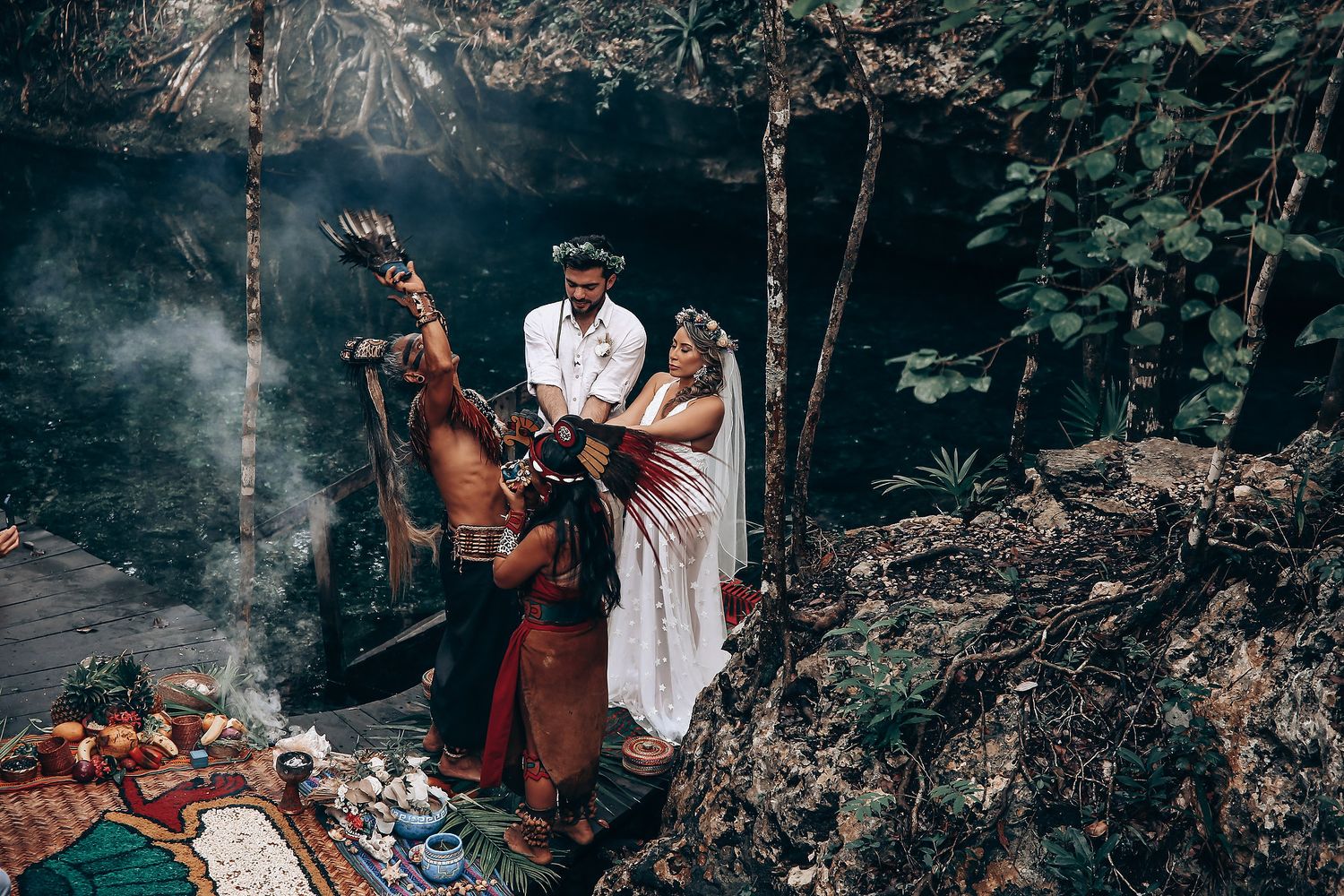 Atmospheric forest wedding scene with smoke and natural light filtering through the trees.