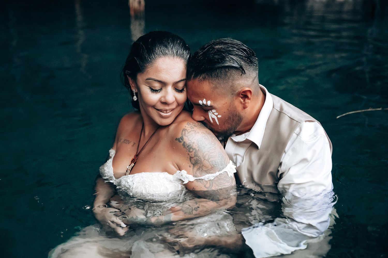 Couple shares romantic moment in cenote water during wedding photo session.