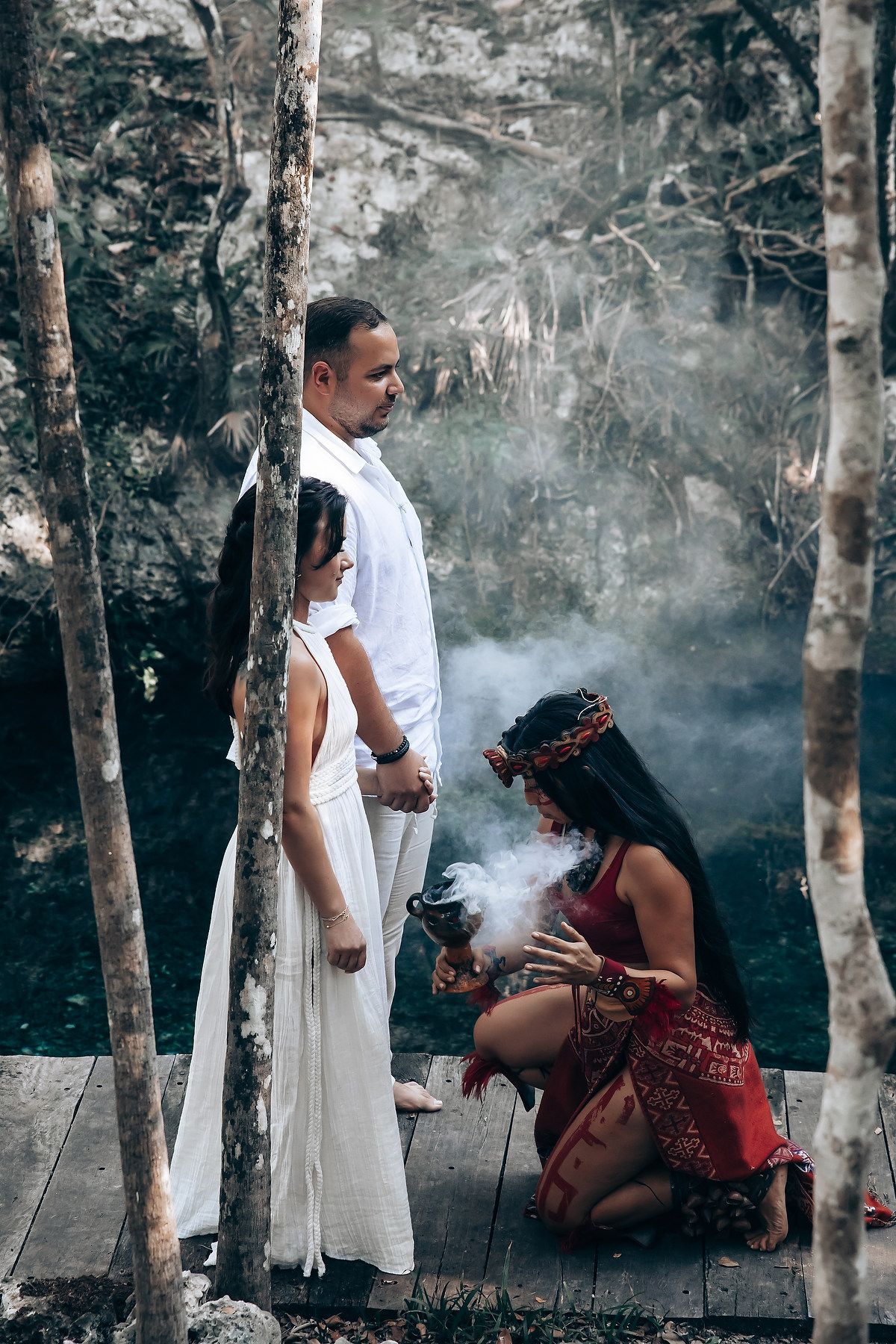 A mystical forest scene with smoke and ritual elements featuring two people in traditional and modern attire.