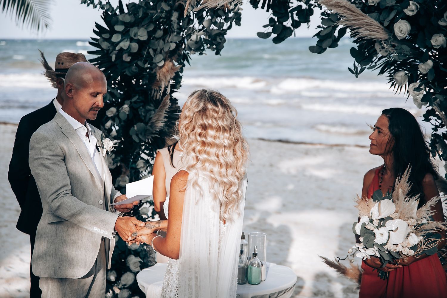 A beachside wedding ceremony setup with tropical foliage and ocean views.