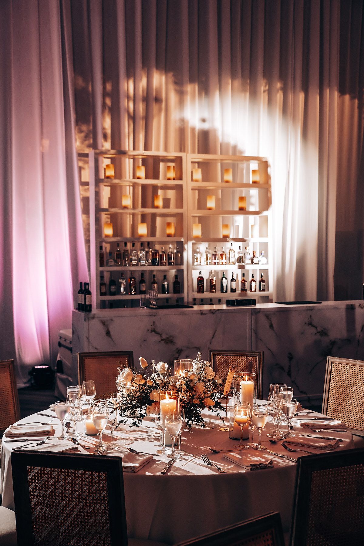 Elegant wedding reception table setting with mood lighting, wine glasses and candles.