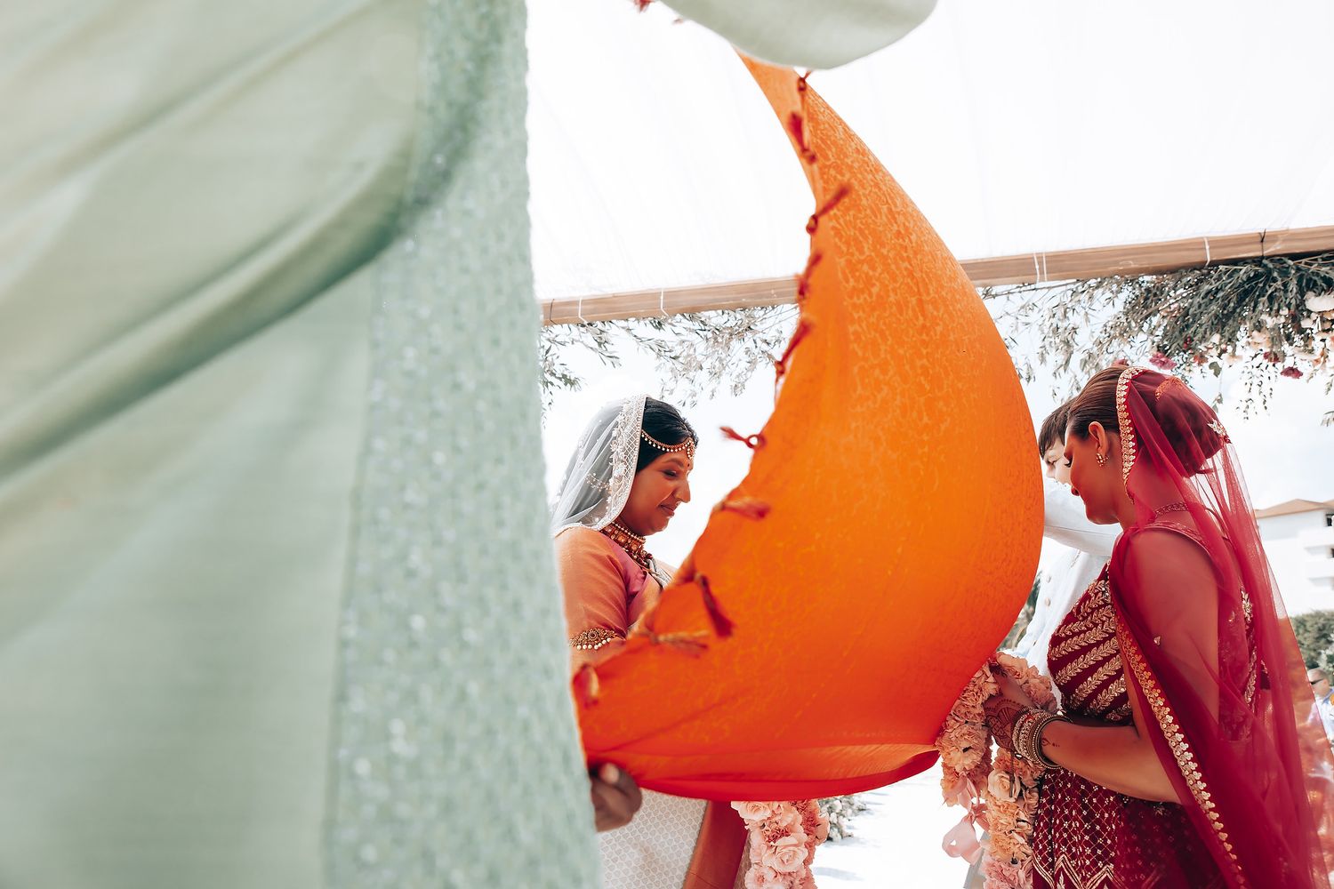 Vibrant orange and red fabric draping creates dramatic wedding ceremony backdrop.