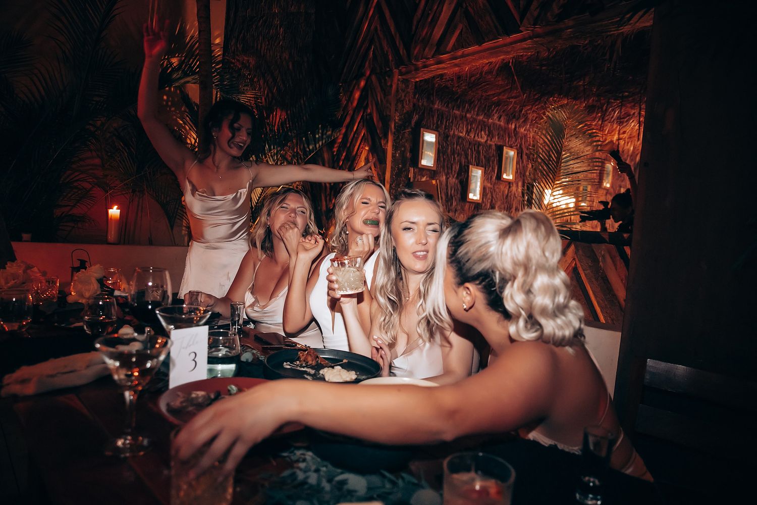 Energetic crowd dancing and partying in a dimly lit nightclub with red lighting effects.