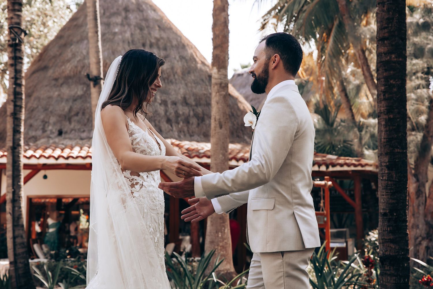 Newlywed couple shares intimate dance moments in an outdoor garden setting with palm trees and rustic architecture.
