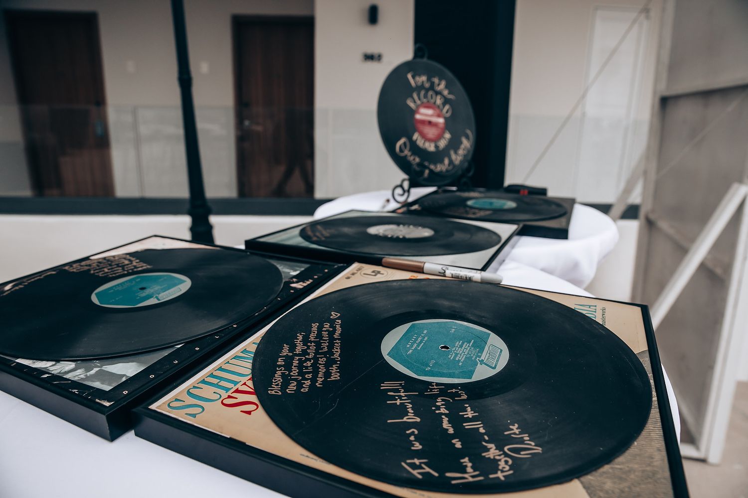 Several vinyl records laid out on a rustic wooden surface with handwritten text visible on their labels.