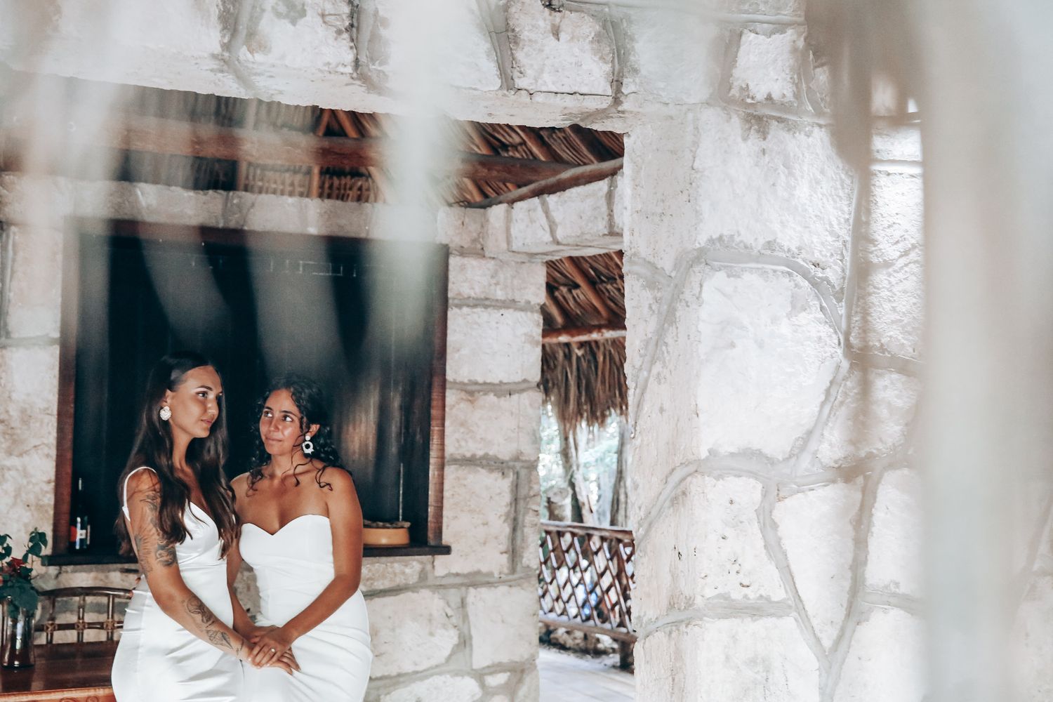 White draped wedding venue interior with rustic wooden beams and natural lighting.