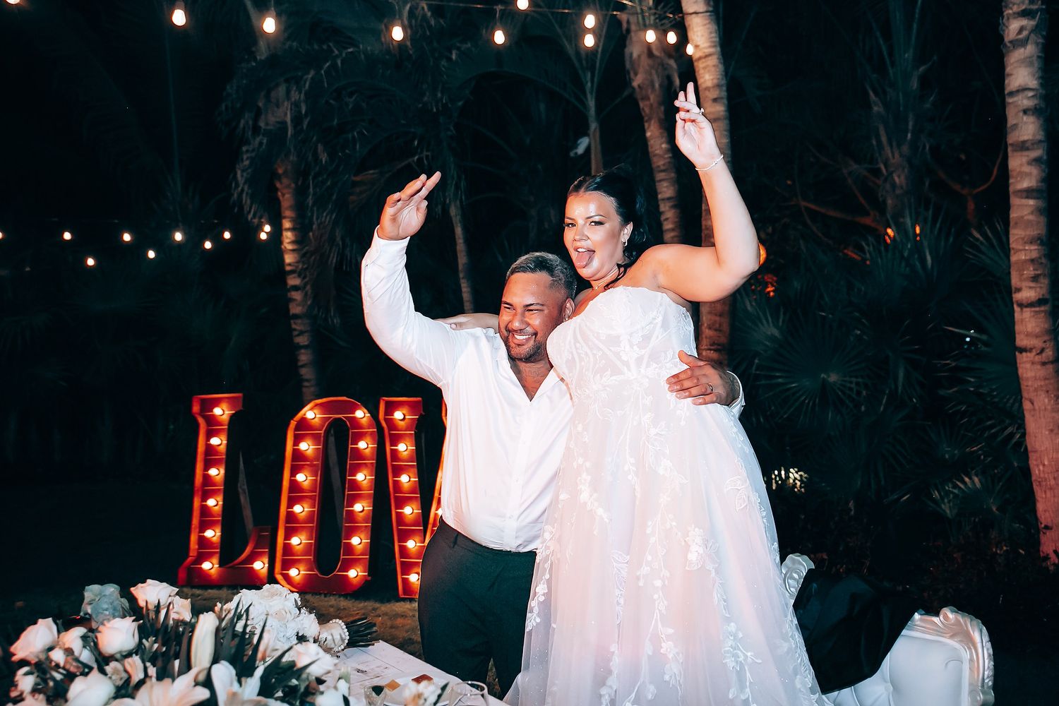 Evening wedding celebration with guests dancing under twinkling string lights.