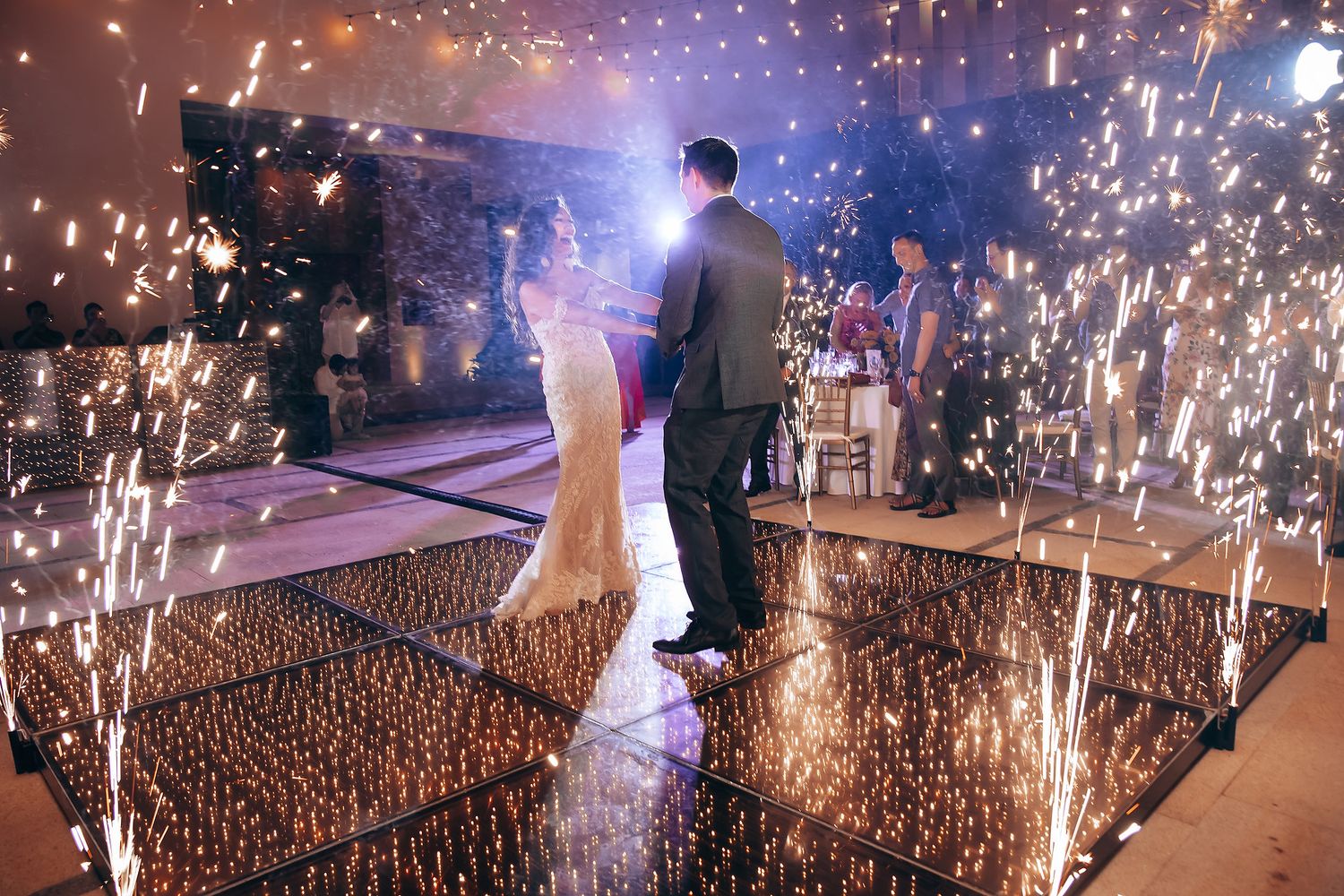 Wedding reception dance floor illuminated with dramatic sparkler effects and lighting.