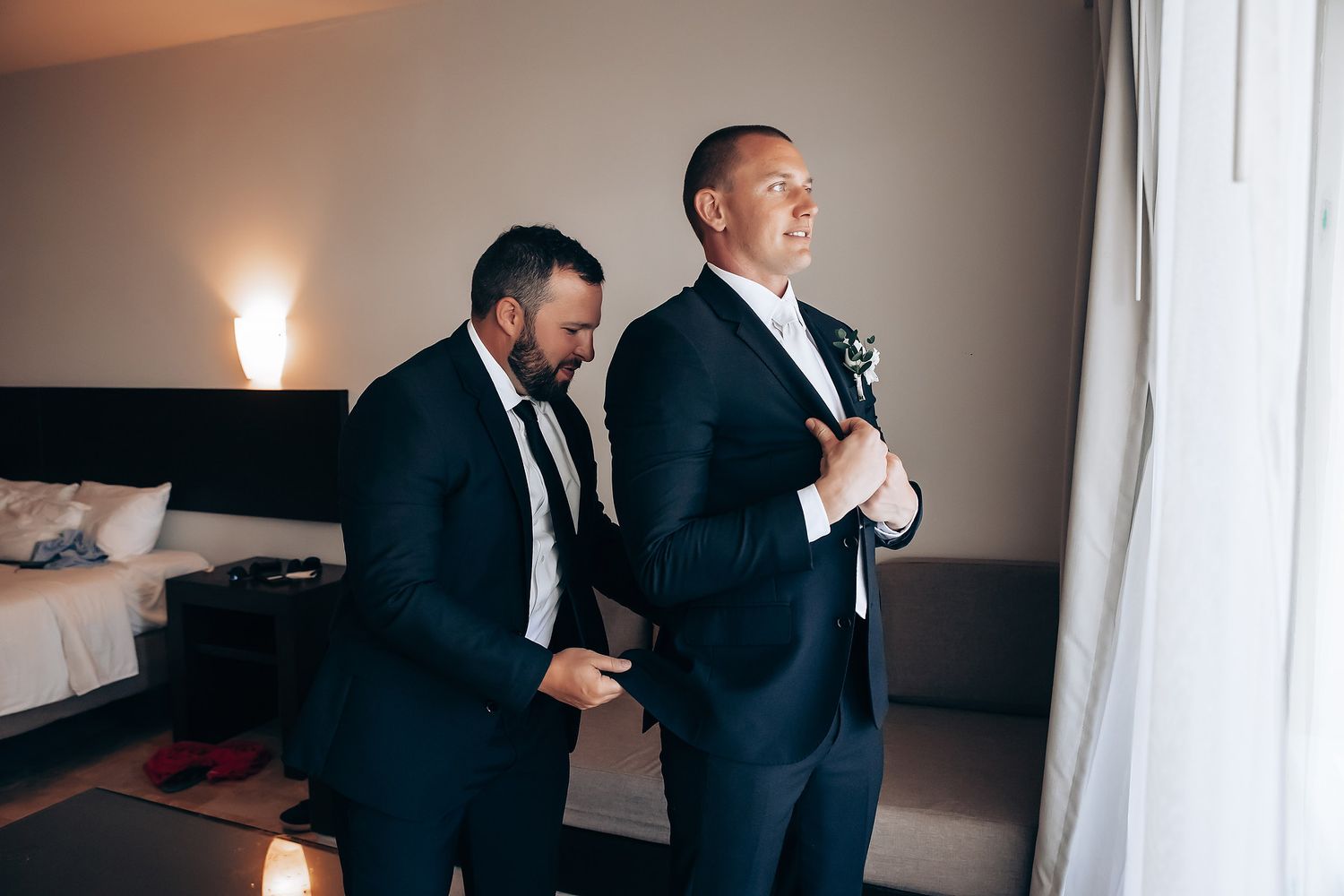 Wedding party members in black suits stand together during formal preparations.