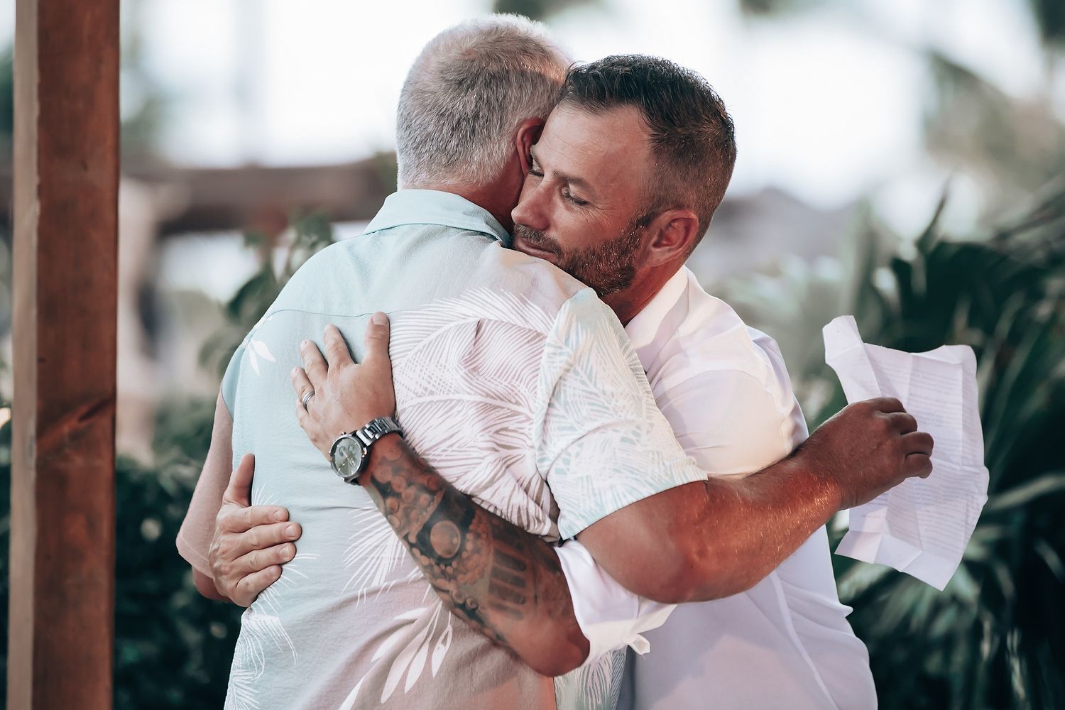 Two men embracing and showing affection in an outdoor setting.