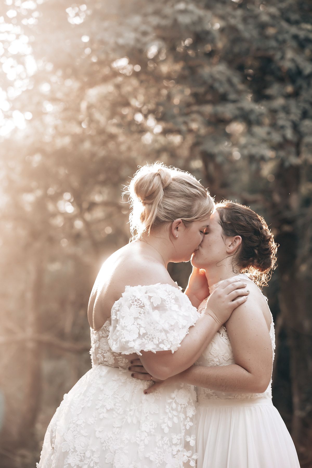 The image shows the hands of a bride and groom, each holding a bouquet of flowers, in a lush, forested setting.